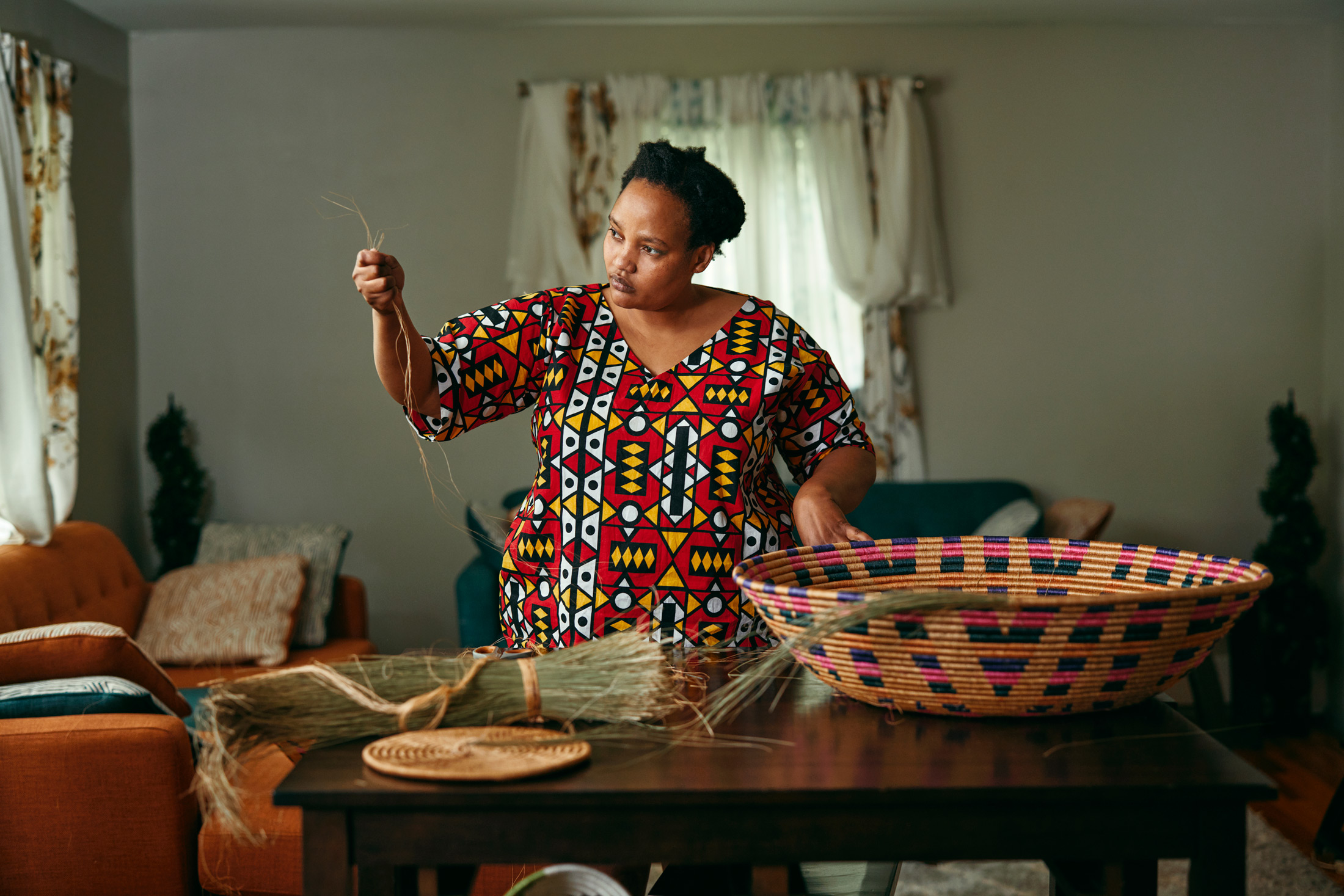 Photo of Muhorakeye Ange preparing materials to weave a basket in front of her in vibrant colors Photo taken by Michael David Wilson, a photographer based in Maine - Agaseke | Black Owned Maine Portland