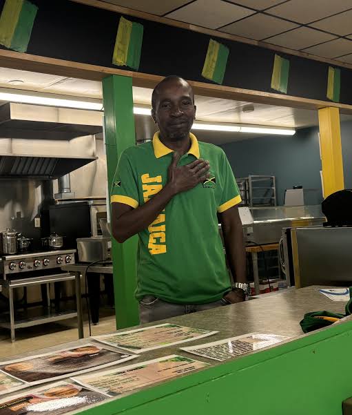 Photo of Kool Runnins owner Walton Wray in a green and yellow shirt that says Jamaica on the side | Black Owned Maine Portland African Restaurant