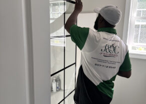 Photo of man installing a shower door - black paned glass door in a white bathroom | Black Owned Maine Portland