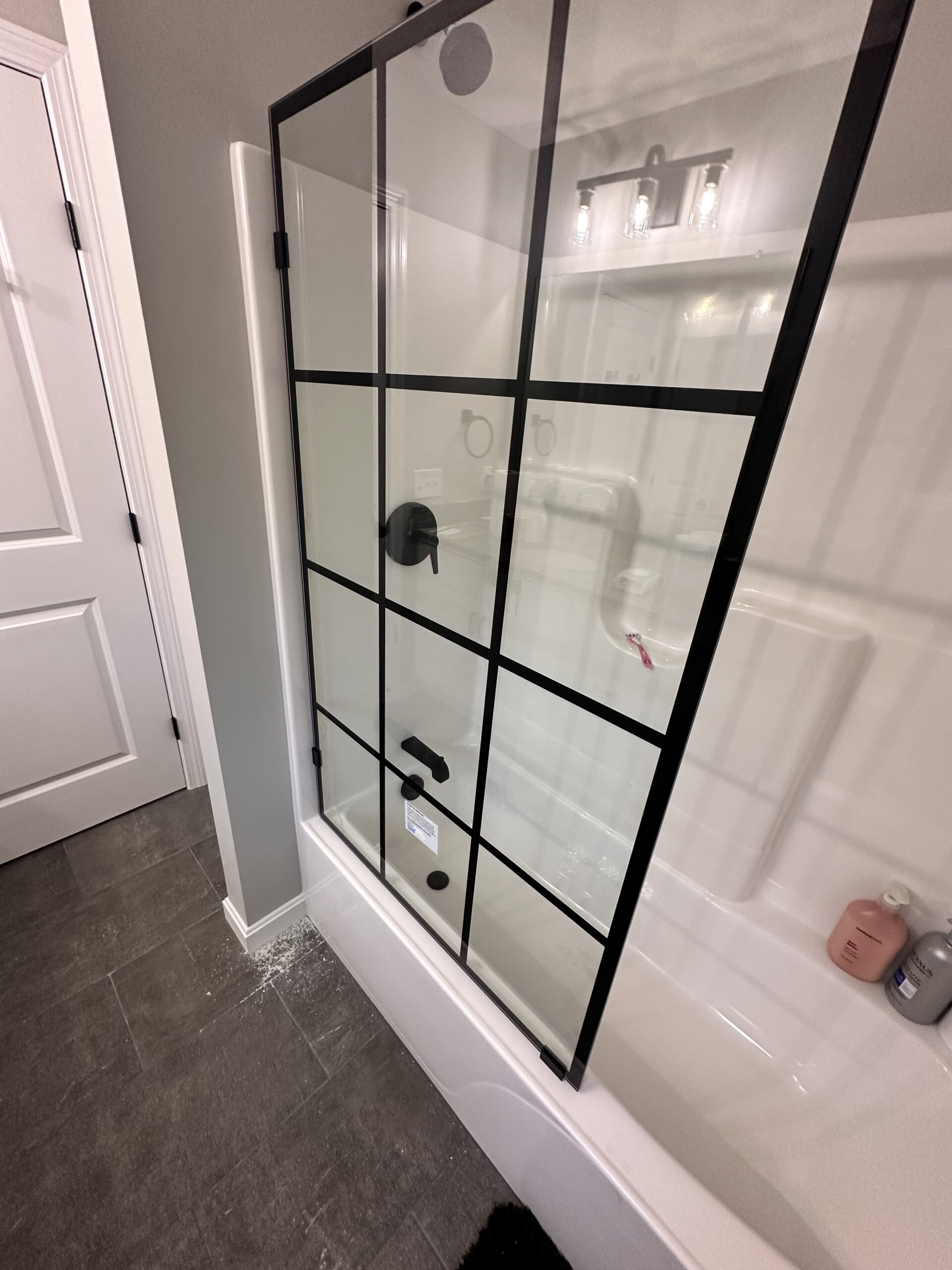 Photo of the finished shower door install - a black paned glass door in a white bathroom | Black Owned Maine Portland